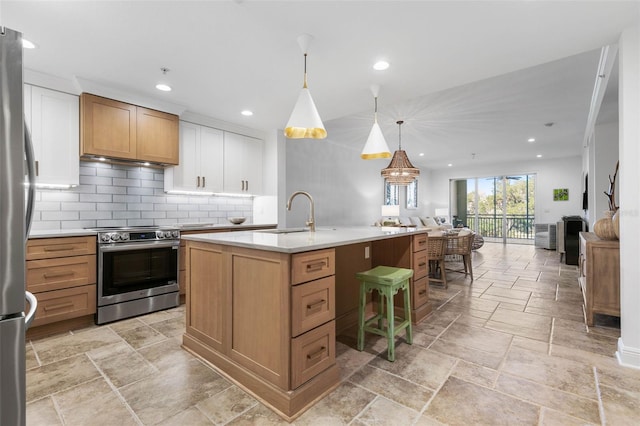 kitchen with decorative light fixtures, backsplash, an island with sink, appliances with stainless steel finishes, and sink