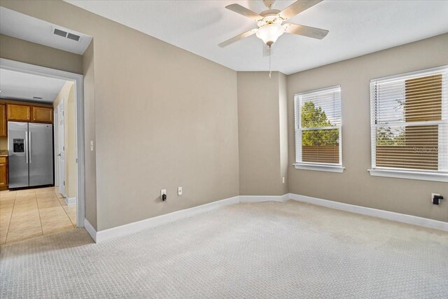 unfurnished room with visible vents, ceiling fan, light carpet, and baseboards