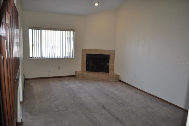 unfurnished living room with a tiled fireplace and carpet floors