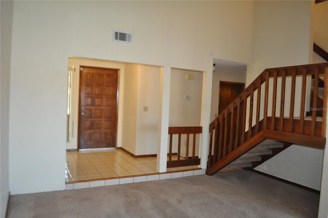 staircase featuring a towering ceiling and carpet