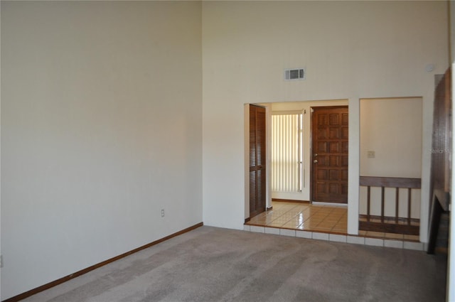 spare room with a towering ceiling and carpet flooring