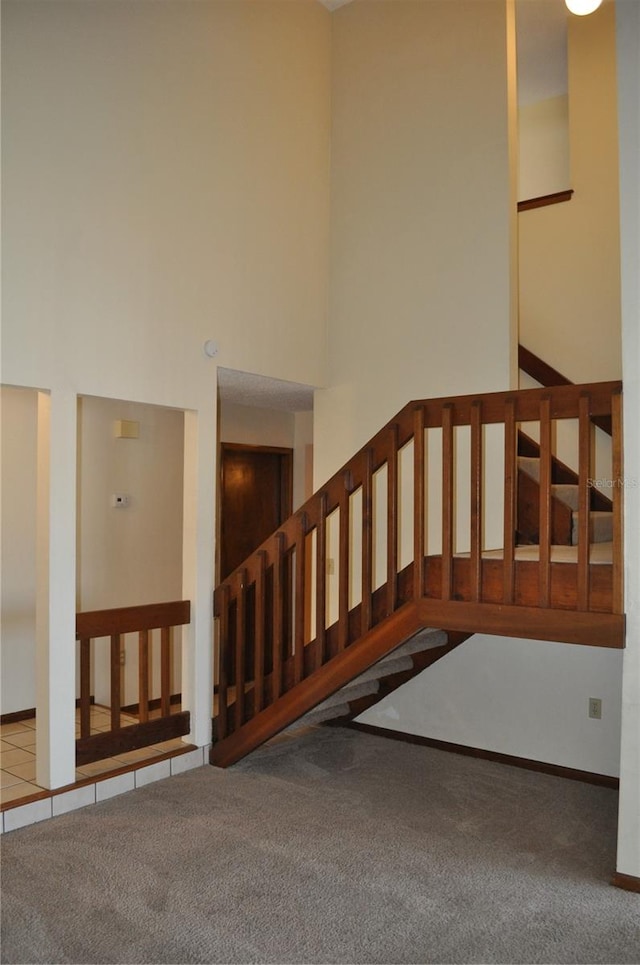 stairs with a high ceiling and carpet floors