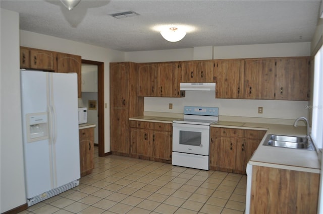 kitchen featuring sink, a textured ceiling, white appliances, and light tile floors