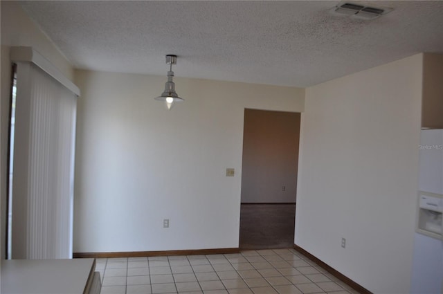 tiled spare room featuring a textured ceiling