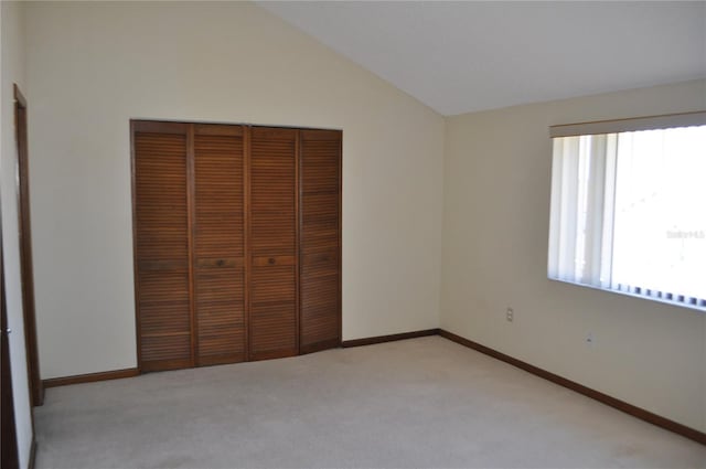 unfurnished bedroom with a closet, carpet flooring, and vaulted ceiling