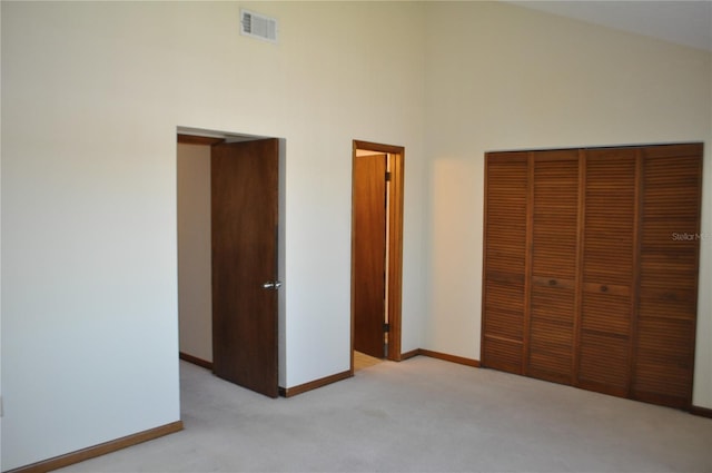 unfurnished bedroom featuring carpet flooring, a towering ceiling, and a closet