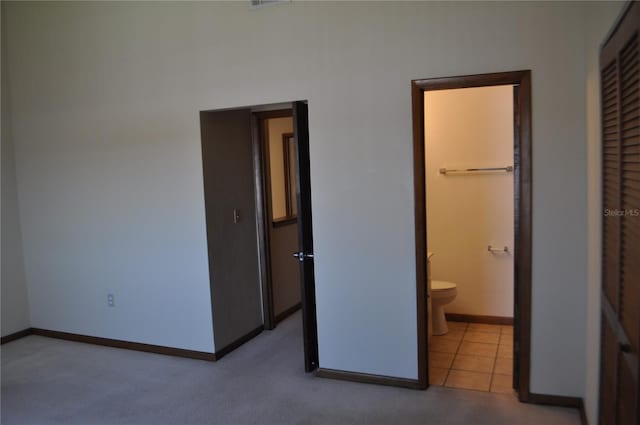 unfurnished bedroom featuring ensuite bath, a walk in closet, a closet, and carpet flooring