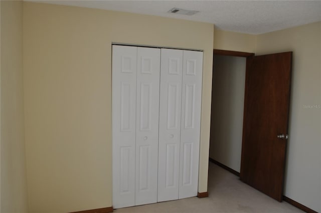 unfurnished bedroom with a closet, a textured ceiling, and light carpet