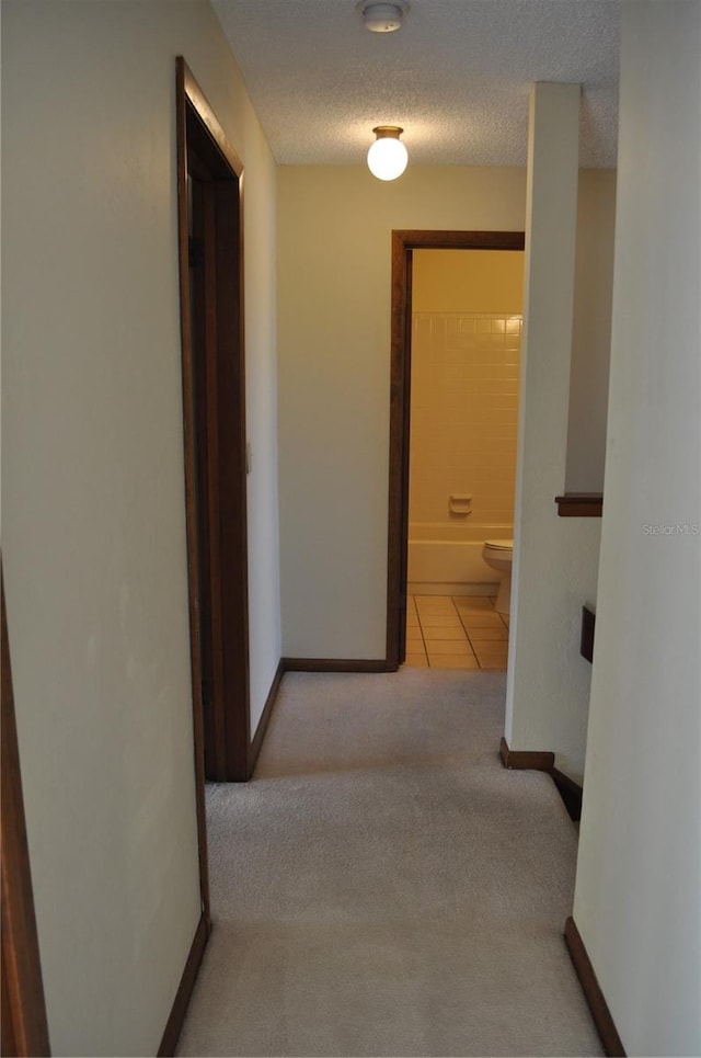 hallway featuring a textured ceiling and tile flooring