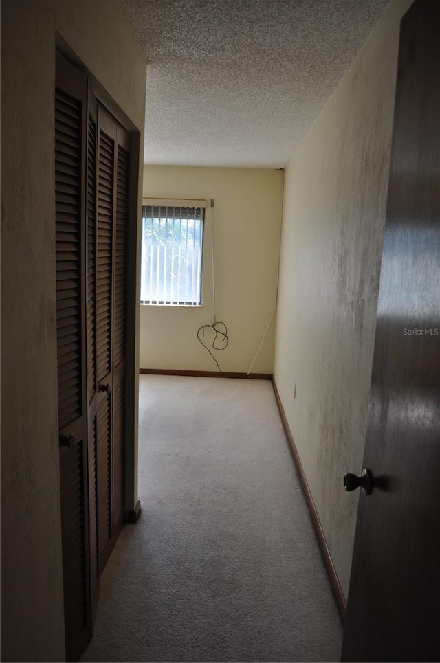 corridor featuring a textured ceiling and carpet flooring