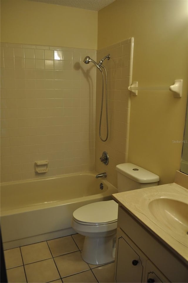 full bathroom featuring oversized vanity, tiled shower / bath, a textured ceiling, tile floors, and toilet