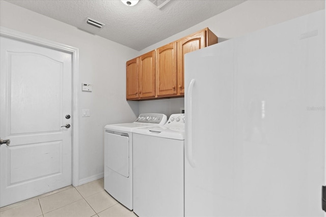 laundry area with washer and clothes dryer, light tile patterned flooring, cabinets, and a textured ceiling