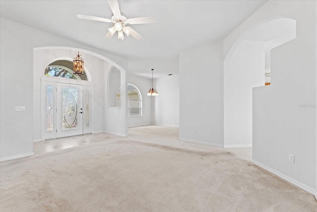 carpeted entryway featuring ceiling fan with notable chandelier