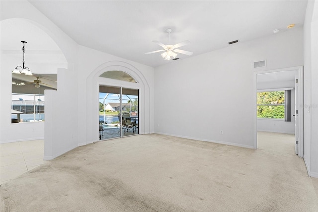 unfurnished room with ceiling fan with notable chandelier, light carpet, and a wealth of natural light