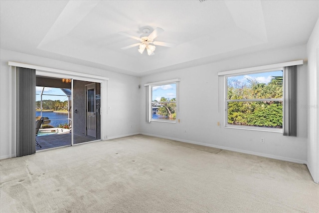 unfurnished room featuring a tray ceiling, plenty of natural light, and a water view