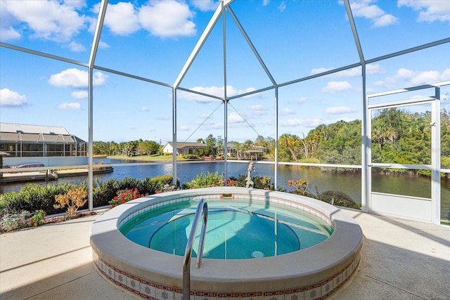 view of pool featuring glass enclosure, a water view, and a hot tub