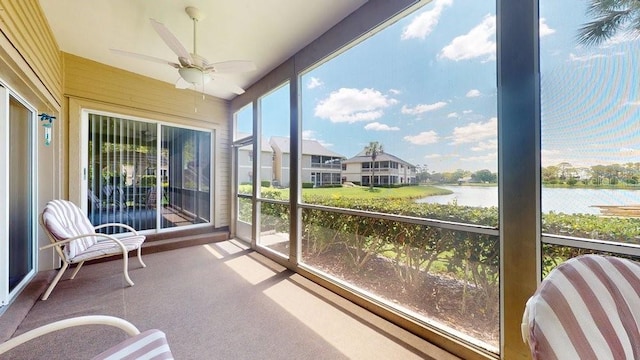 sunroom / solarium with ceiling fan and a water view