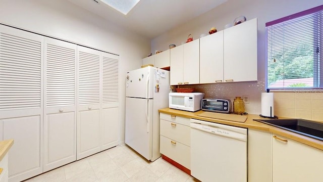 kitchen with white cabinetry, white appliances, light tile floors, and tasteful backsplash