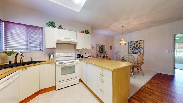 kitchen featuring light hardwood / wood-style flooring, white appliances, decorative light fixtures, sink, and white cabinetry