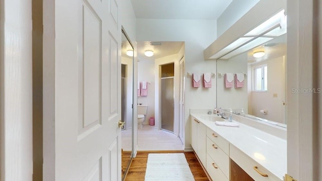 bathroom with vanity with extensive cabinet space, hardwood / wood-style flooring, and toilet