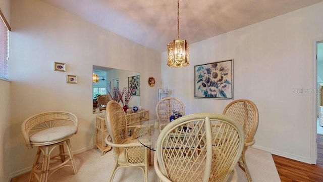 dining area with wood-type flooring, an inviting chandelier, and lofted ceiling