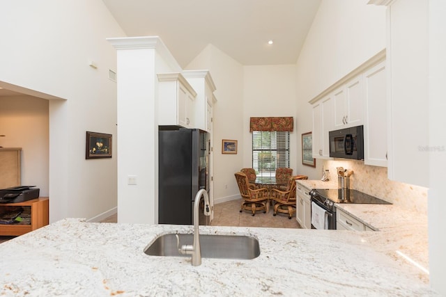 kitchen featuring black appliances, white cabinets, sink, tasteful backsplash, and light tile floors