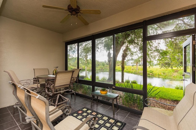 sunroom / solarium with ceiling fan, a healthy amount of sunlight, and a water view
