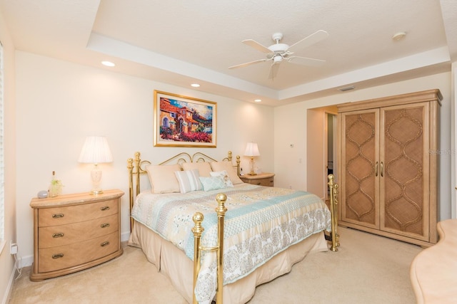 bedroom featuring ceiling fan, a raised ceiling, and light carpet