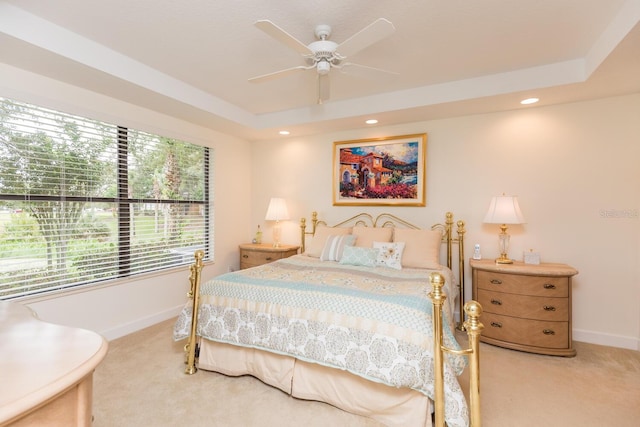 carpeted bedroom featuring ceiling fan and a tray ceiling