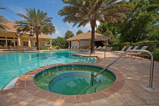 view of swimming pool with a hot tub and a patio