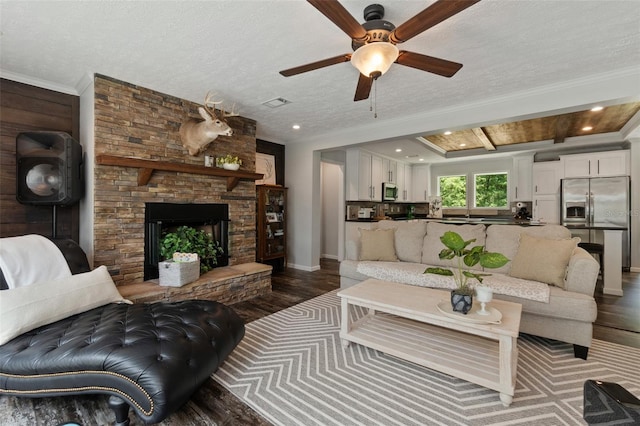 living room featuring dark hardwood / wood-style floors, ceiling fan, a fireplace, and a textured ceiling