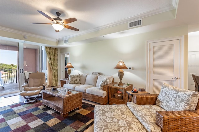 living room with ceiling fan, a raised ceiling, crown molding, and tile patterned floors