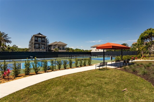 surrounding community featuring tennis court and a lawn