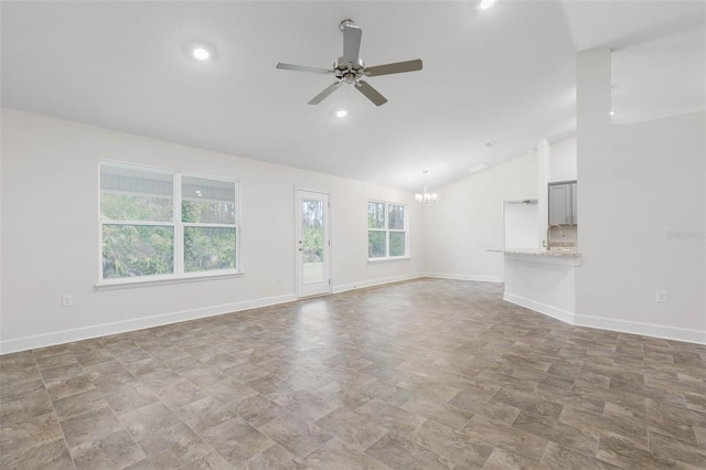 unfurnished living room with ceiling fan with notable chandelier and vaulted ceiling