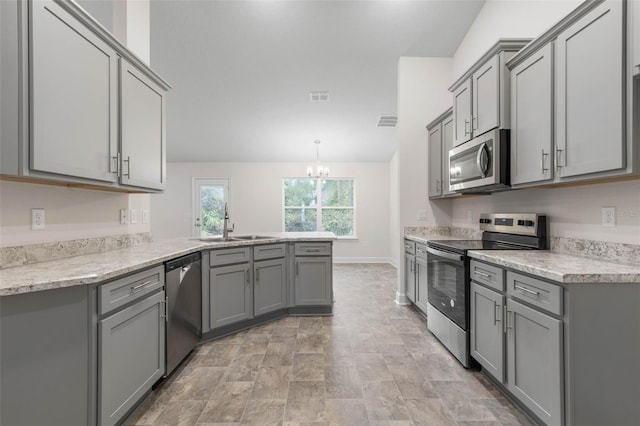 kitchen with pendant lighting, appliances with stainless steel finishes, gray cabinetry, a notable chandelier, and kitchen peninsula