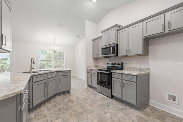 kitchen with pendant lighting, sink, lofted ceiling, gray cabinetry, and stainless steel appliances