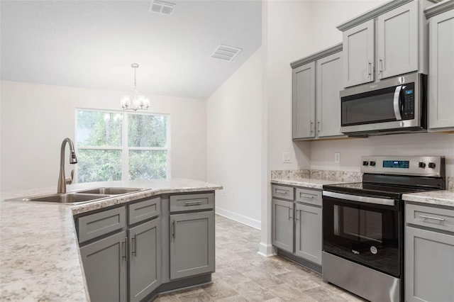 kitchen featuring appliances with stainless steel finishes, decorative light fixtures, sink, gray cabinetry, and a chandelier