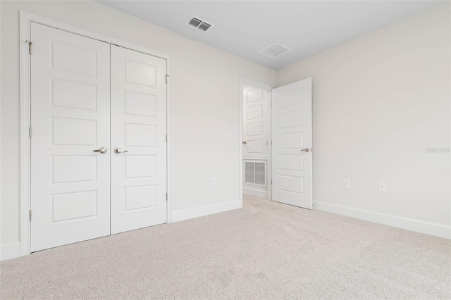 unfurnished bedroom with light carpet and a closet