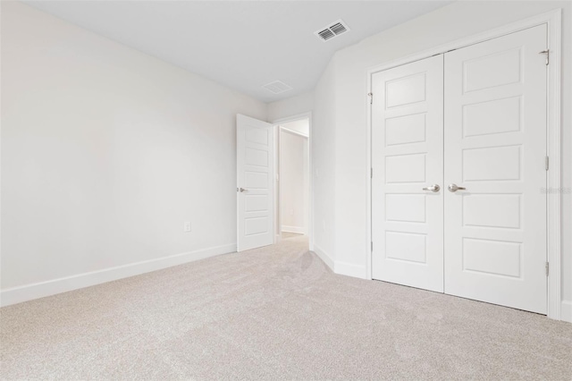 unfurnished bedroom featuring light carpet and a closet