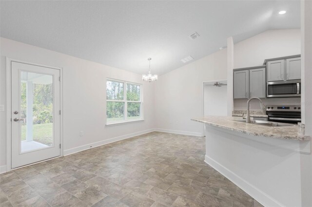 kitchen featuring lofted ceiling, gray cabinetry, pendant lighting, stainless steel appliances, and light stone countertops