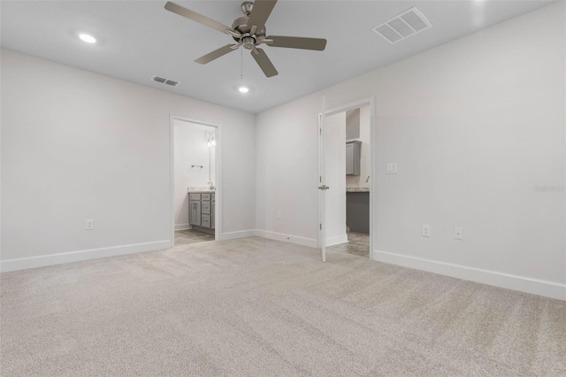 unfurnished bedroom featuring connected bathroom, light colored carpet, and ceiling fan