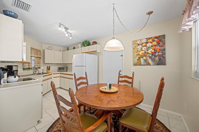 dining area with light tile patterned floors, a textured ceiling, and sink