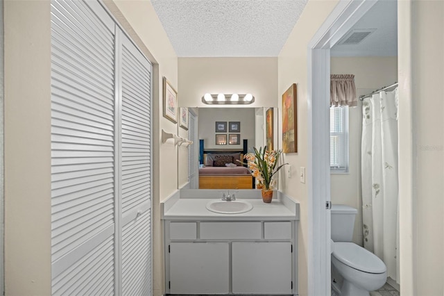 bathroom with vanity, a textured ceiling, and toilet