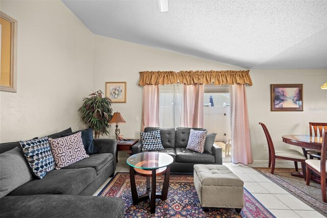 living room featuring a textured ceiling, light tile patterned floors, and lofted ceiling