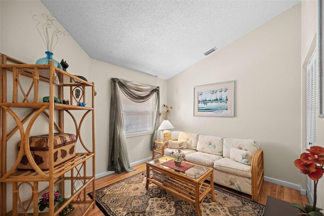 living room featuring hardwood / wood-style floors, a textured ceiling, and vaulted ceiling