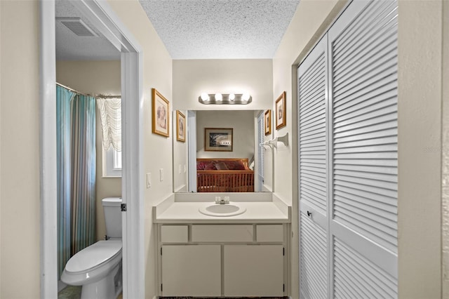 bathroom featuring vanity, a textured ceiling, and toilet