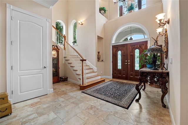 tiled entryway with a healthy amount of sunlight, a towering ceiling, and crown molding