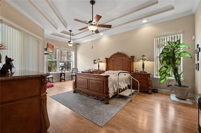 bedroom with ceiling fan, a raised ceiling, light wood-type flooring, and ornamental molding