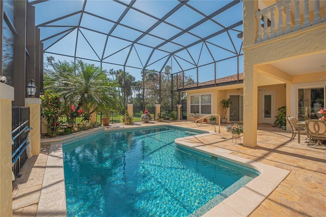 outdoor pool featuring glass enclosure, a patio area, fence, and a ceiling fan