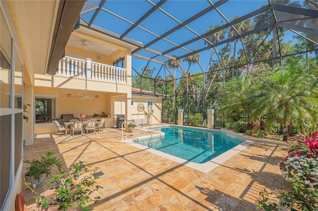 outdoor pool with a patio area, a grill, glass enclosure, and a ceiling fan